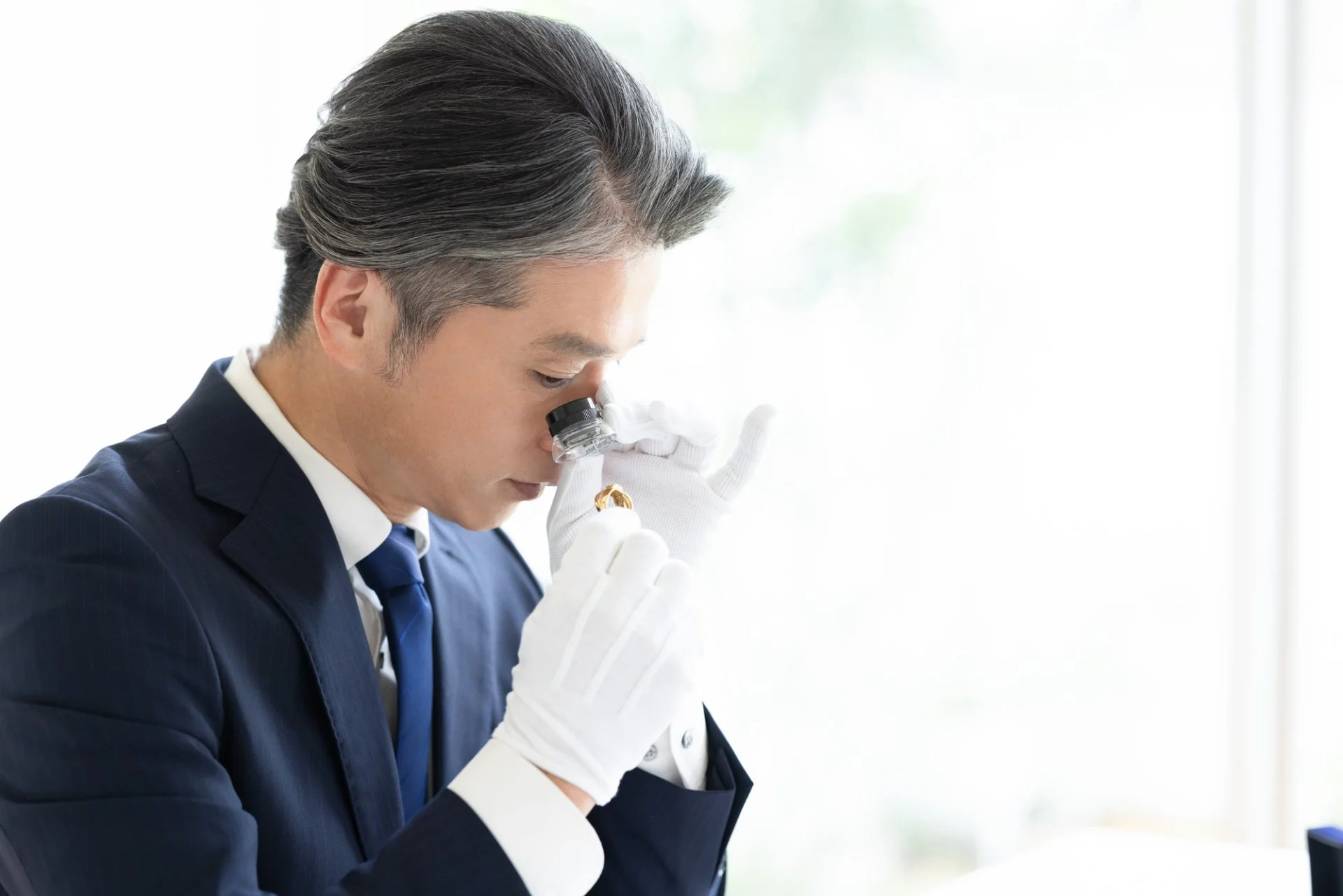 黒い布の上に置かれた金の指輪と細いチェーンのクローズアップ