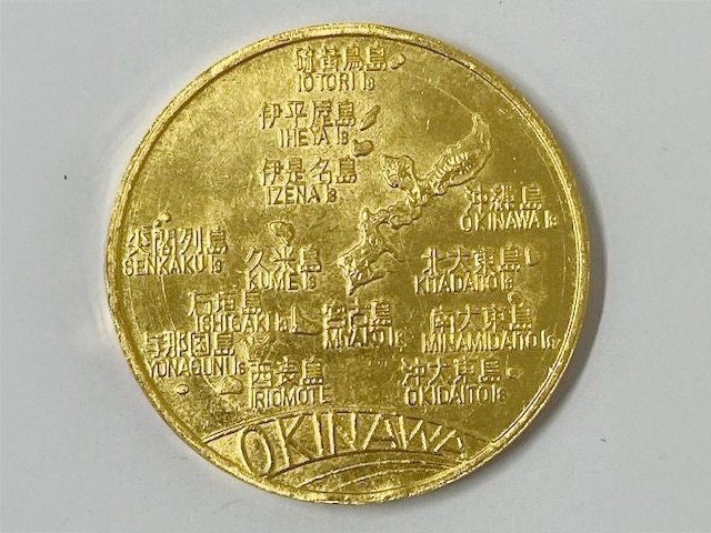 沖縄の島々の地図が刻まれた金色の記念メダル