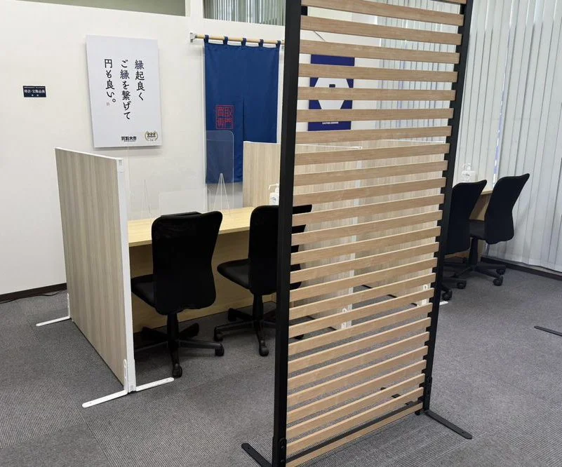 木製パーティションと黒いオフィスチェアが並ぶ買取大吉 那覇天久店の店内カウンター席